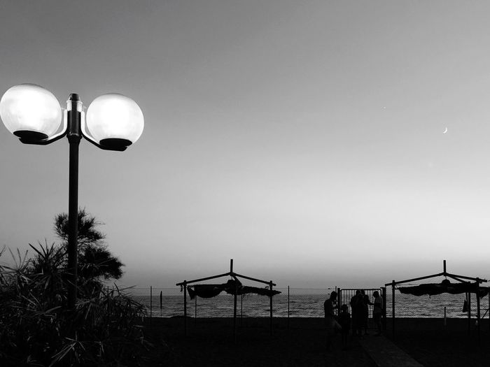 View of street lights on beach against clear sky at dusk