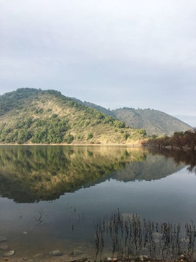 Scenic view of lake by mountain against sky