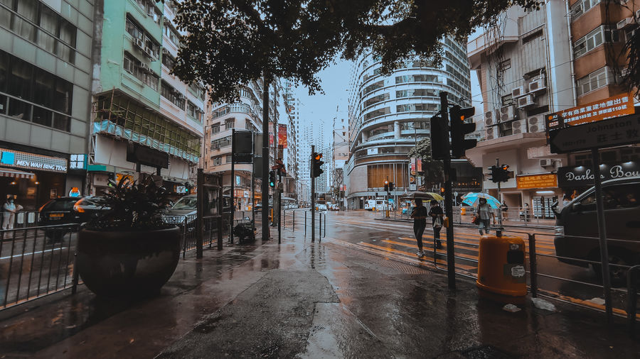 Wet street amidst buildings in city during rainy season
