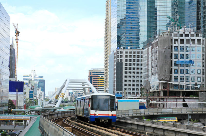 Train on railroad tracks amidst buildings in city against sky