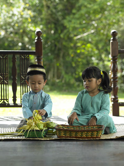 Children in traditional clothing sitting on mat