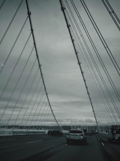 Cars on suspension bridge against sky