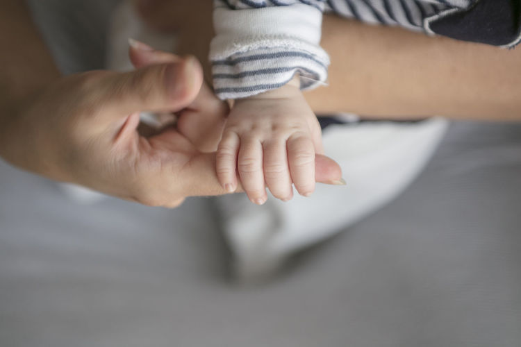 Cropped hands of mother holding newborn