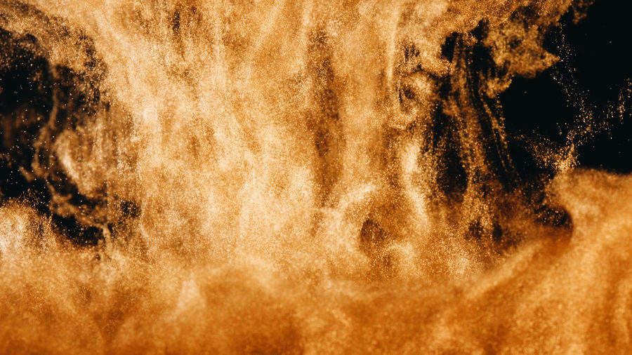 Close-up of golden ink in water against black background