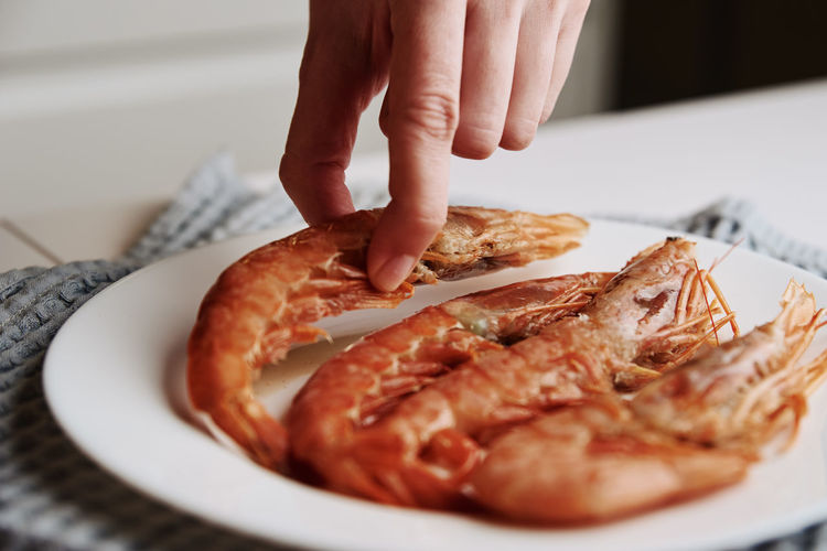 Woman take fresh raw shrimp from plate. cooking prawns