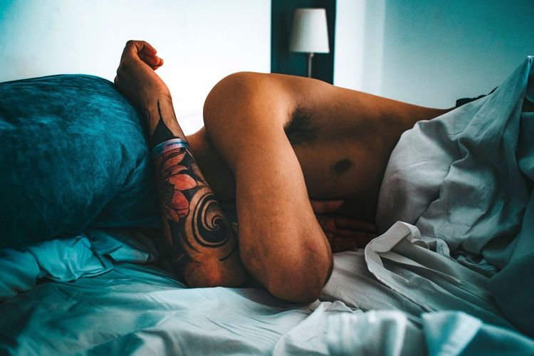 Shirtless man sleeping on bed at home