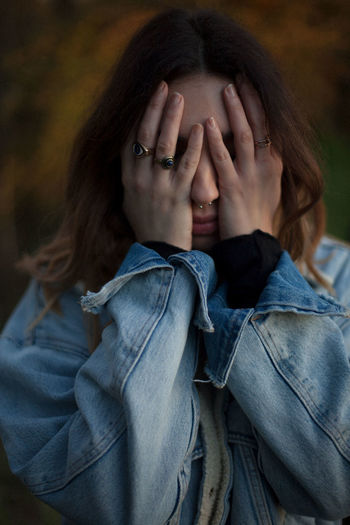 Portrait of woman hiding face covered with hand