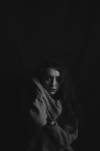 Portrait of woman sitting against black background