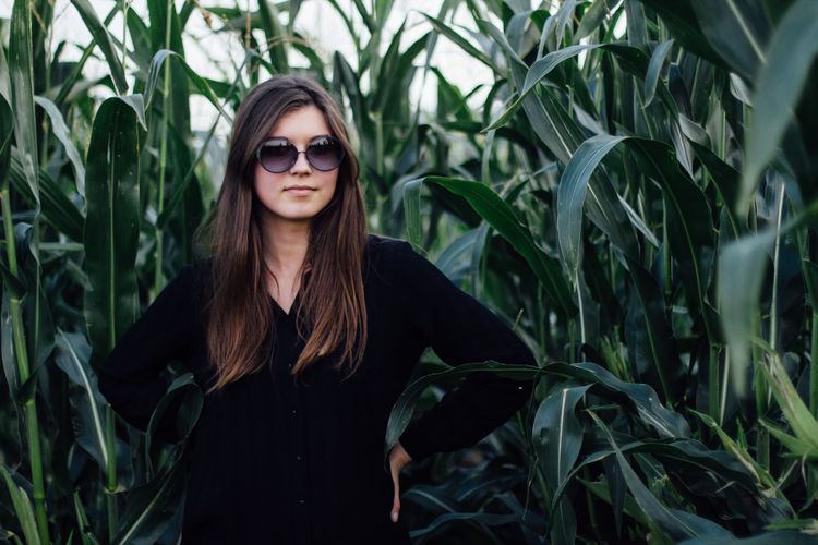 Young woman standing against crops on field