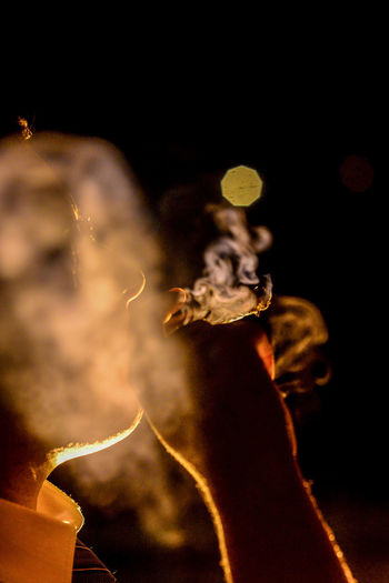 Close-up portrait of illuminated smoking on table at night