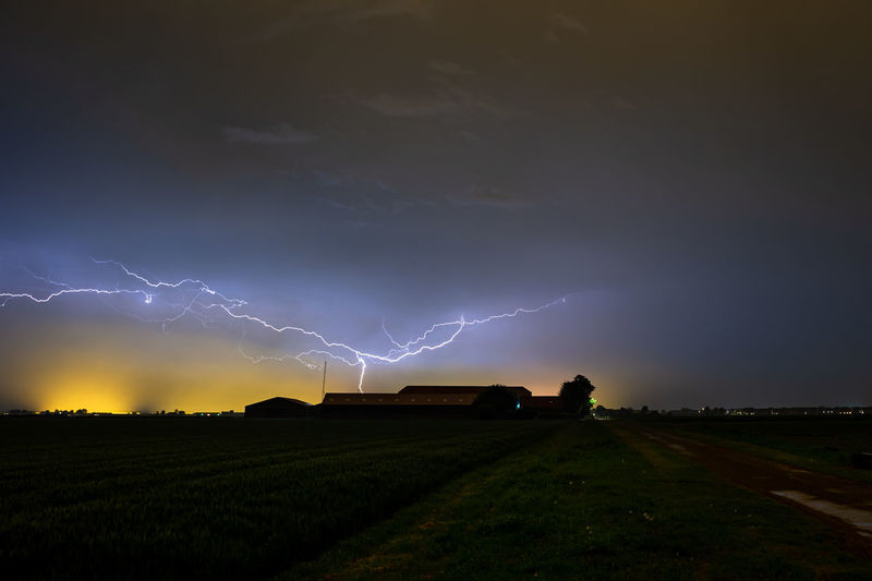 Dramatic image of lightning cleaving the sky above a farm during a thundery night in may