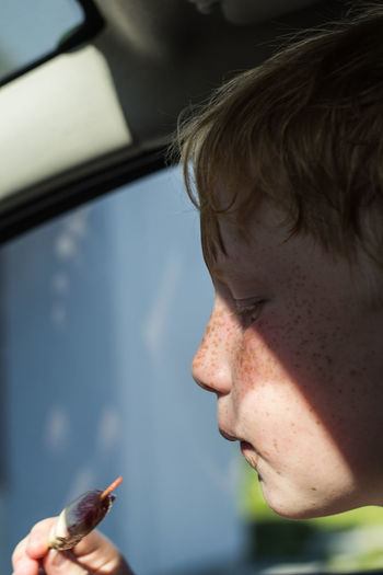 Close-up of boy having food while sitting in car