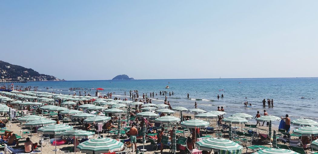 Panoramic view of people on beach against clear sky