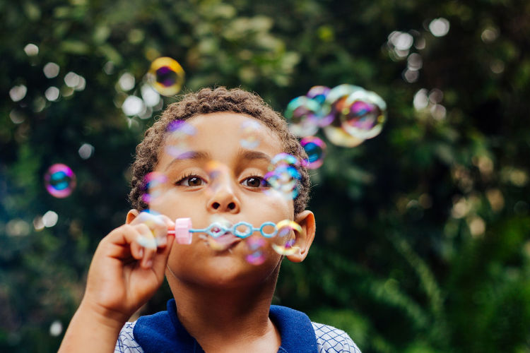 Boy blowing bubbles in park