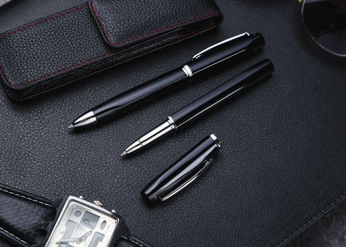 Close-up of pens with wallet and wristwatch