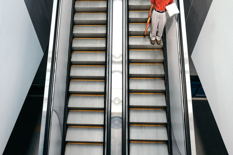 Low section of man standing on escalator