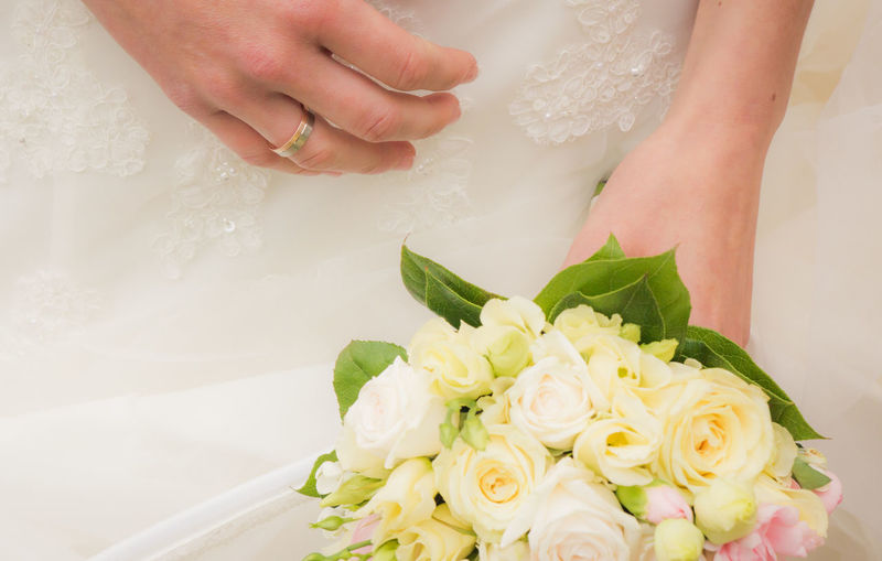 Mid section of a bride holding bouquet