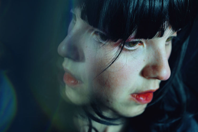 Close-up of woman by glass in darkroom