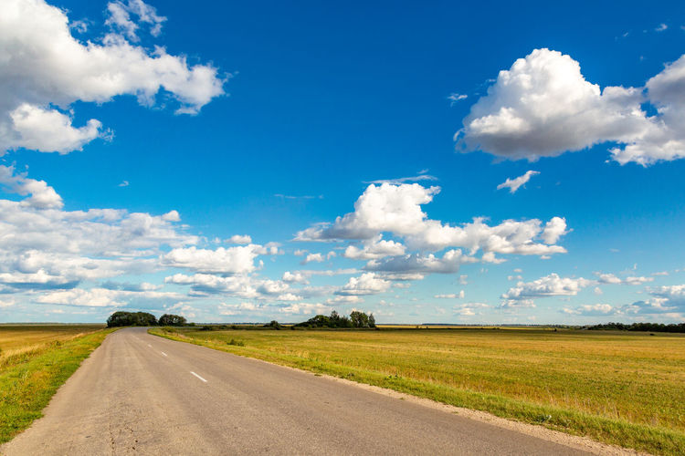 Road amidst field against sky