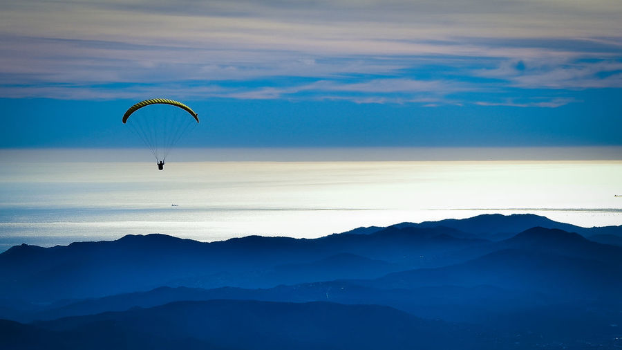 Person paragliding against sea