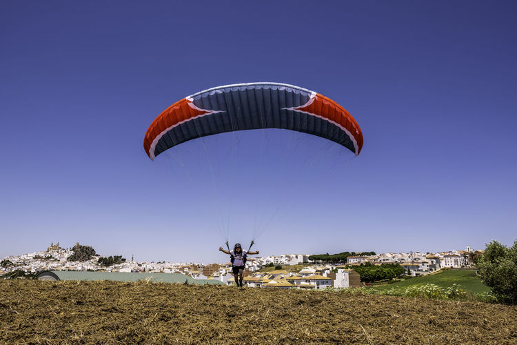 Low angle view of person paragliding against clear blue sky