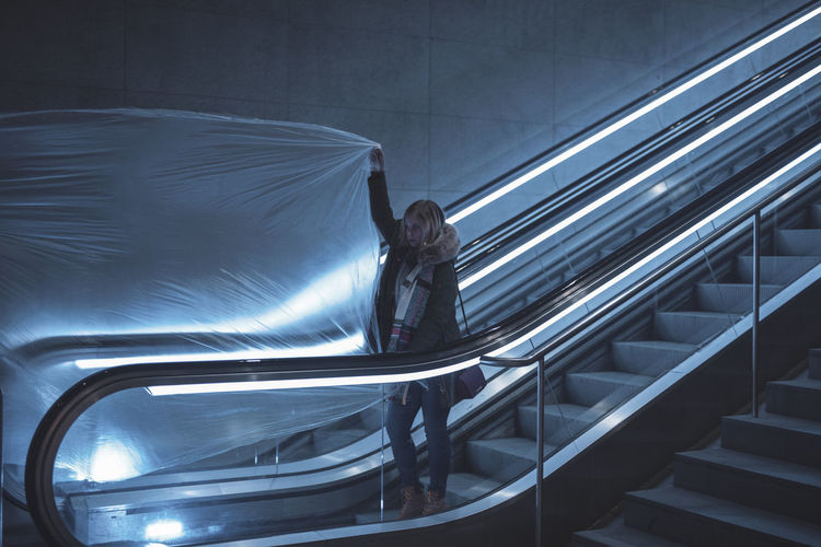 Young woman holding plastic on escalator