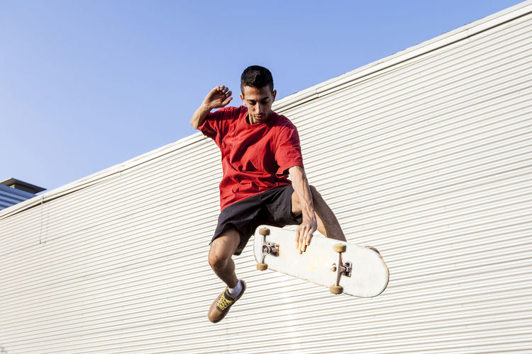 Man with skateboard in mid-air against wall