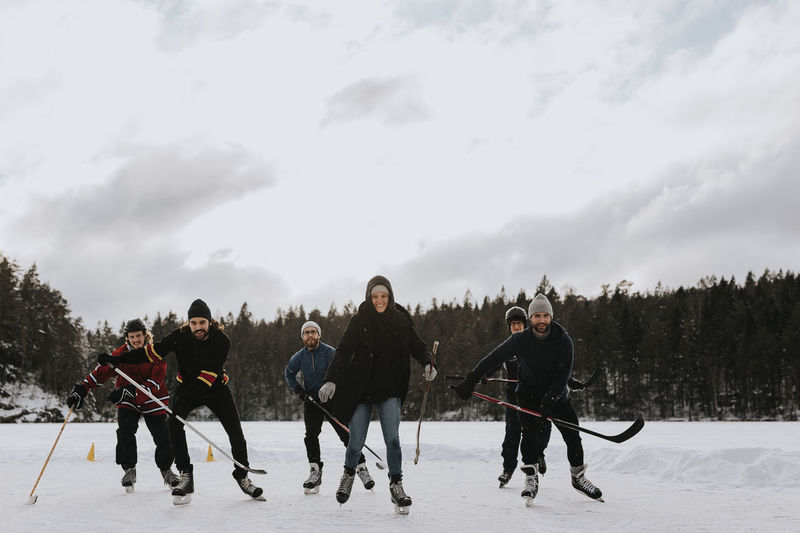 Friends playing hockey on frozen lake