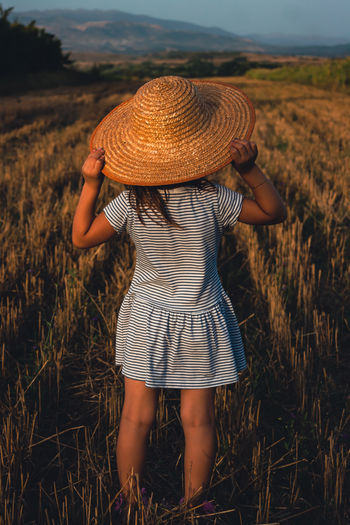 Rear view of woman wearing hat on field