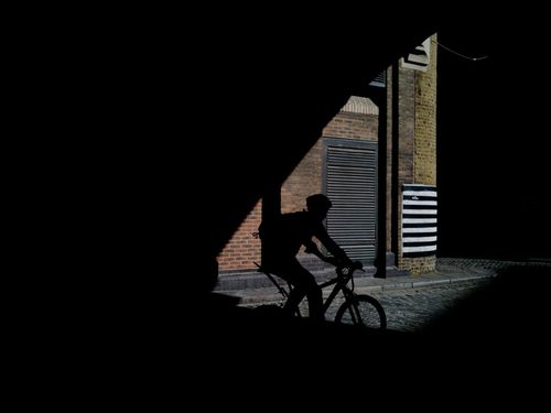 Silhouette man riding bicycle on city street