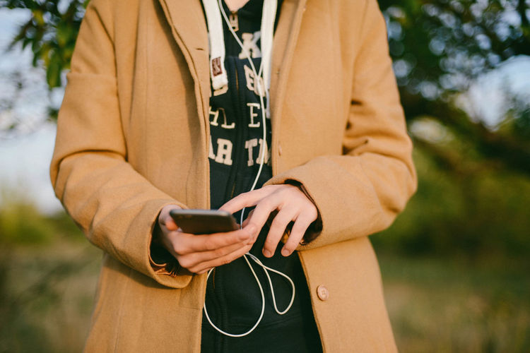 Midsection of woman using phone while standing outdoors