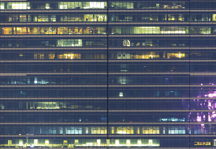 Multi-storey office building at night with worker. late night overtime in a modern office building