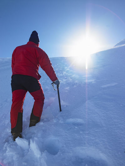 Man hiking up snowy hill towards a summit