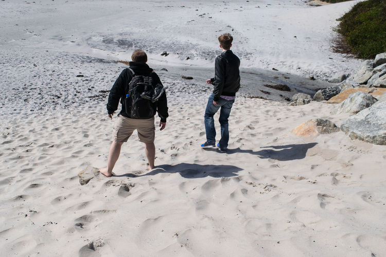 Tourists standing on sand