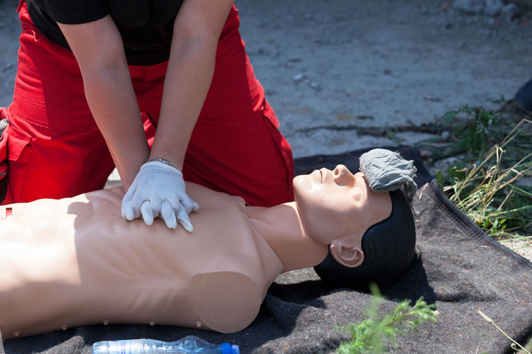 Midsection of lifeguard performing cpr on mannequin