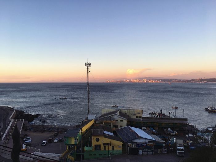 High angle view of buildings by sea against sky during sunset