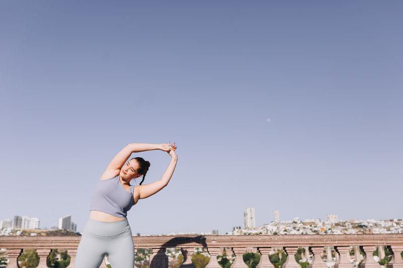 Full length of woman standing by cityscape against sky