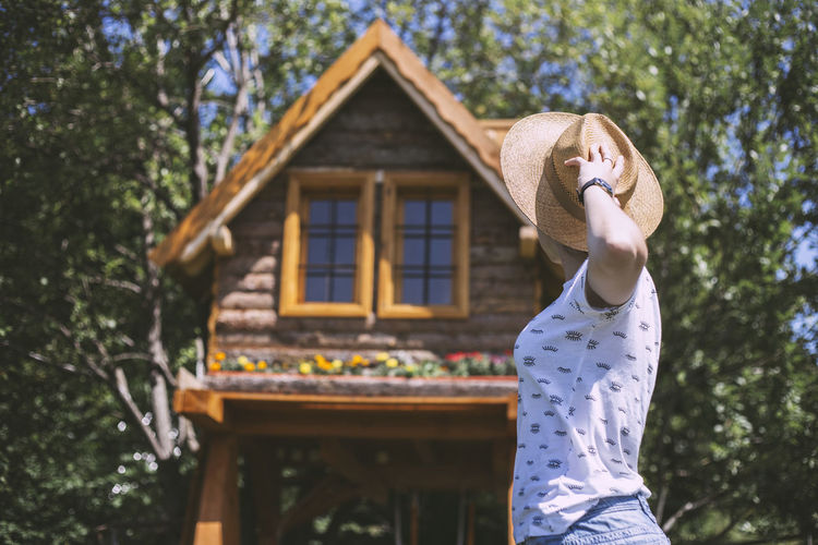 Woman with straw hat looking at wooden cabin