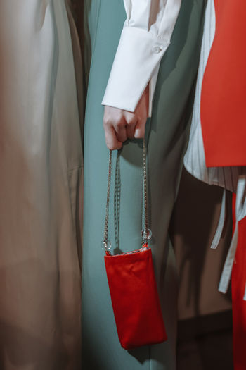 Female hand holding a small red handbag with silver chain