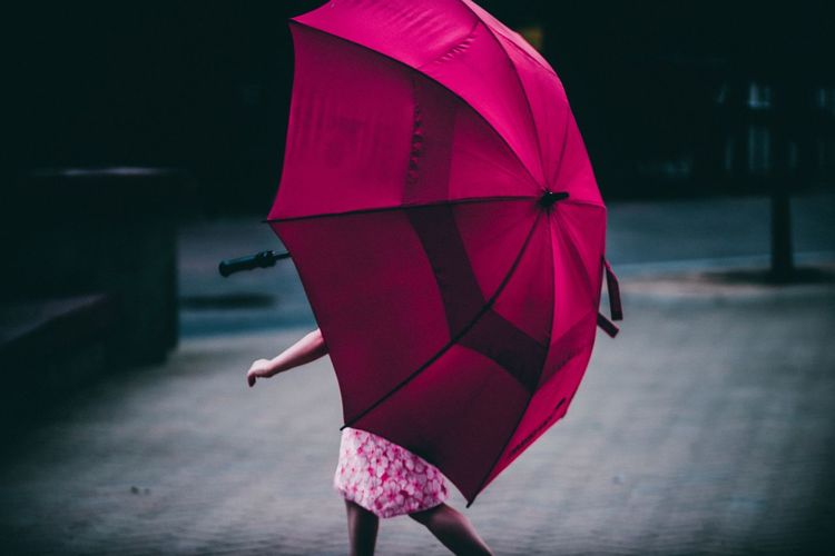Low section of woman standing on pink umbrella