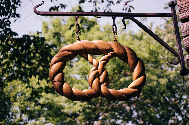 Low angle view of pretzel figurine hanging against trees