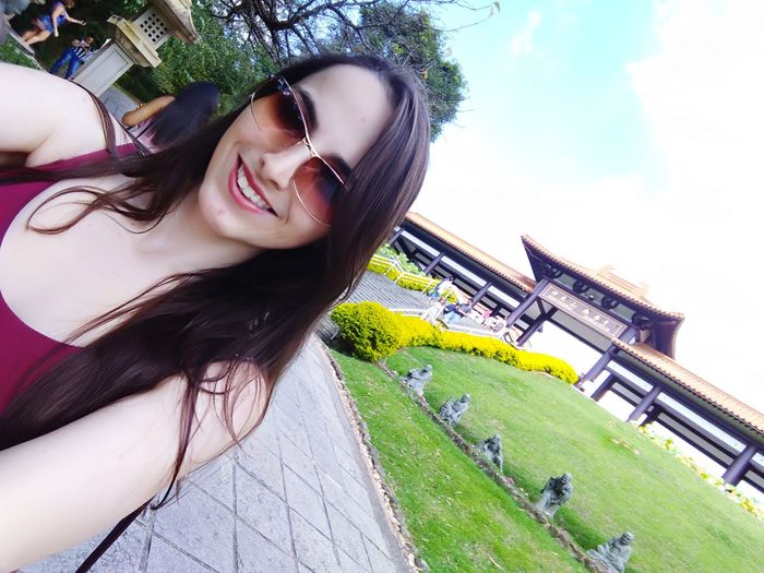 Portrait of smiling young woman against sky