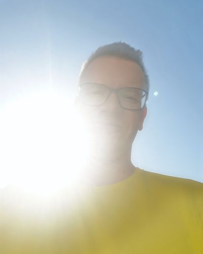 Low angle portrait of man against sky on sunny day