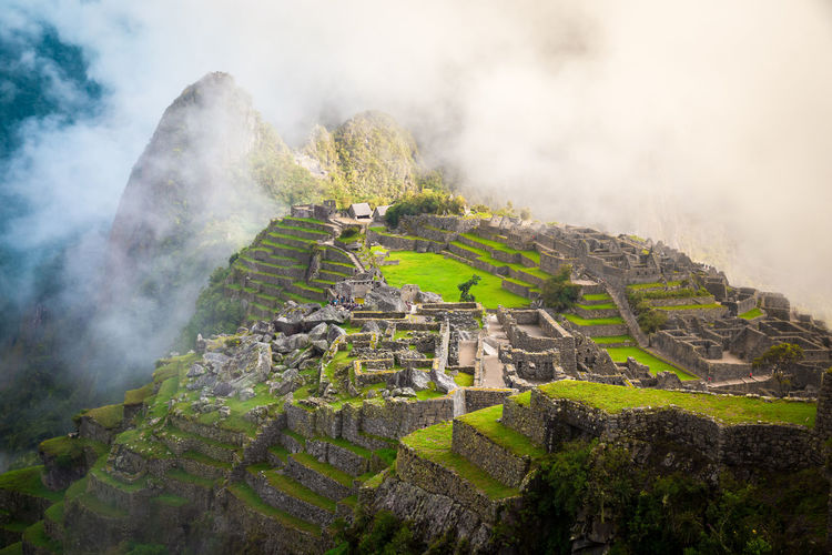 Old ruins on mountain against sky during foggy weather