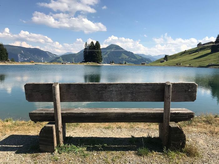 Bench by lake against sky - austria alps