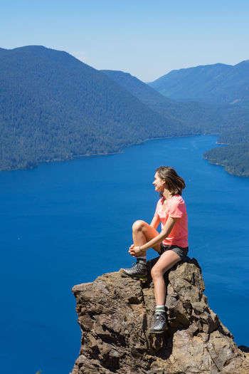 Hiker girl is on top of the mountain overlooking deep blue lake