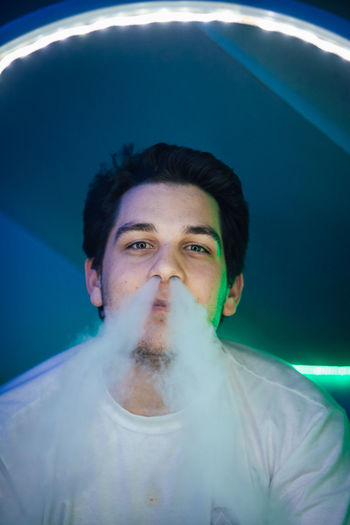 Close-up portrait of young man smoking in club