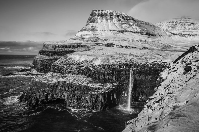 Rock formation by sea against sky