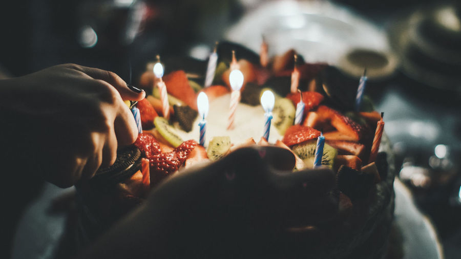 Close-up of woman igniting candles on birthday cake