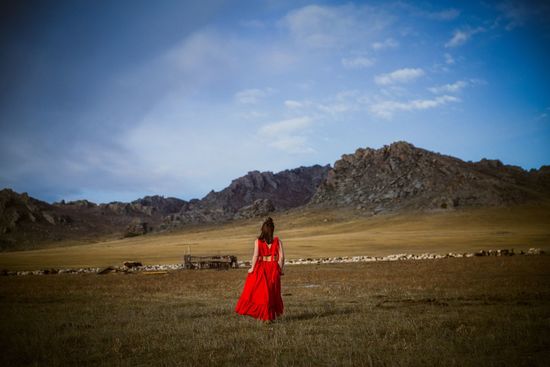 Rear view of woman walking on field against sky